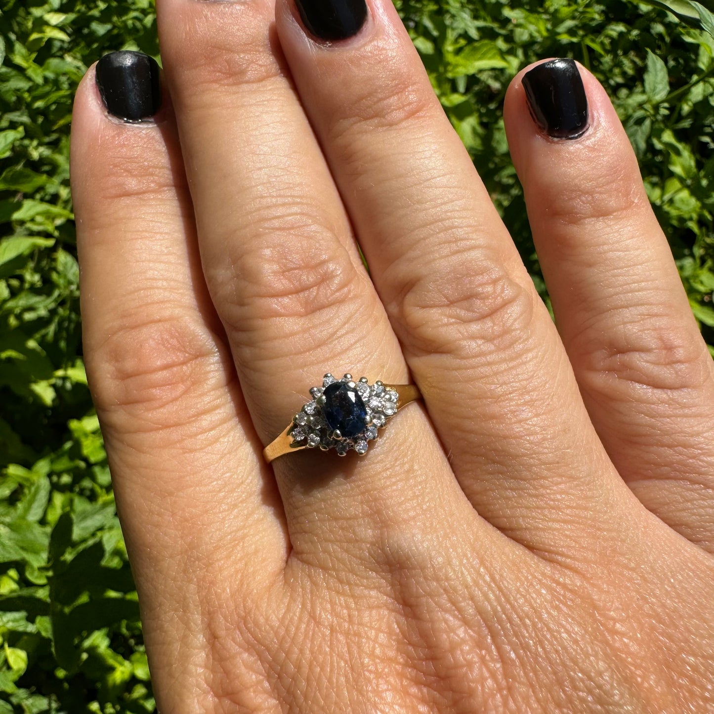 14K gold ring set with an oval blue Sapphire surrounded by sparkling Diamonds