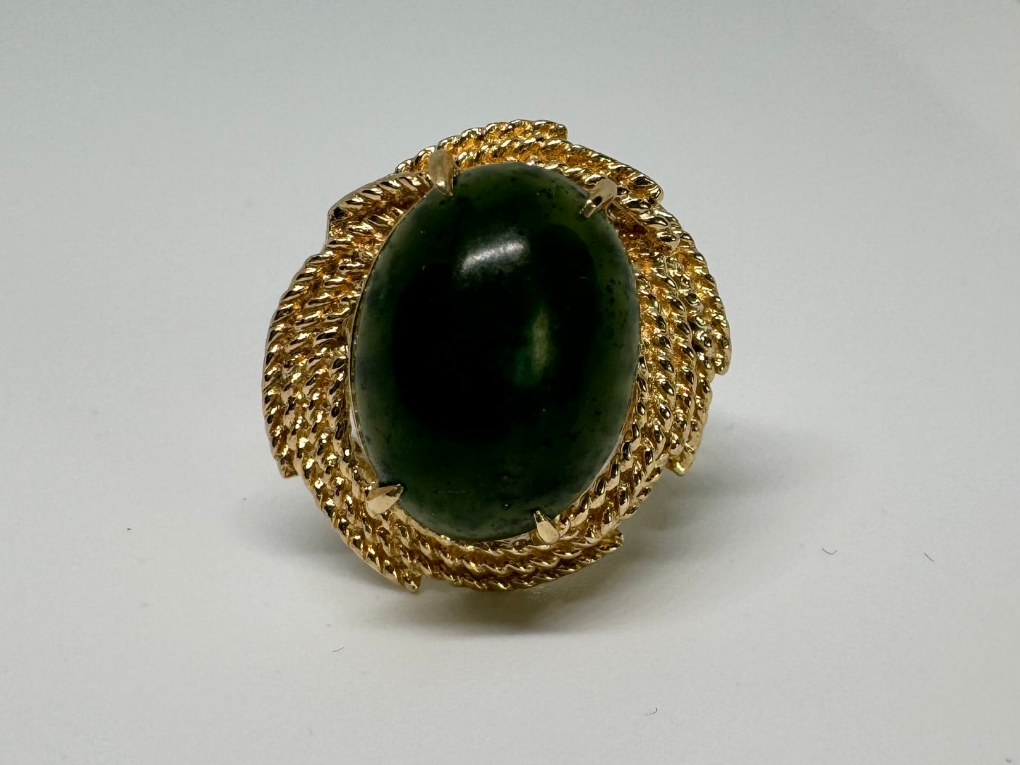 14K gold ring set with a deep green Jade set in a textured gold frame.