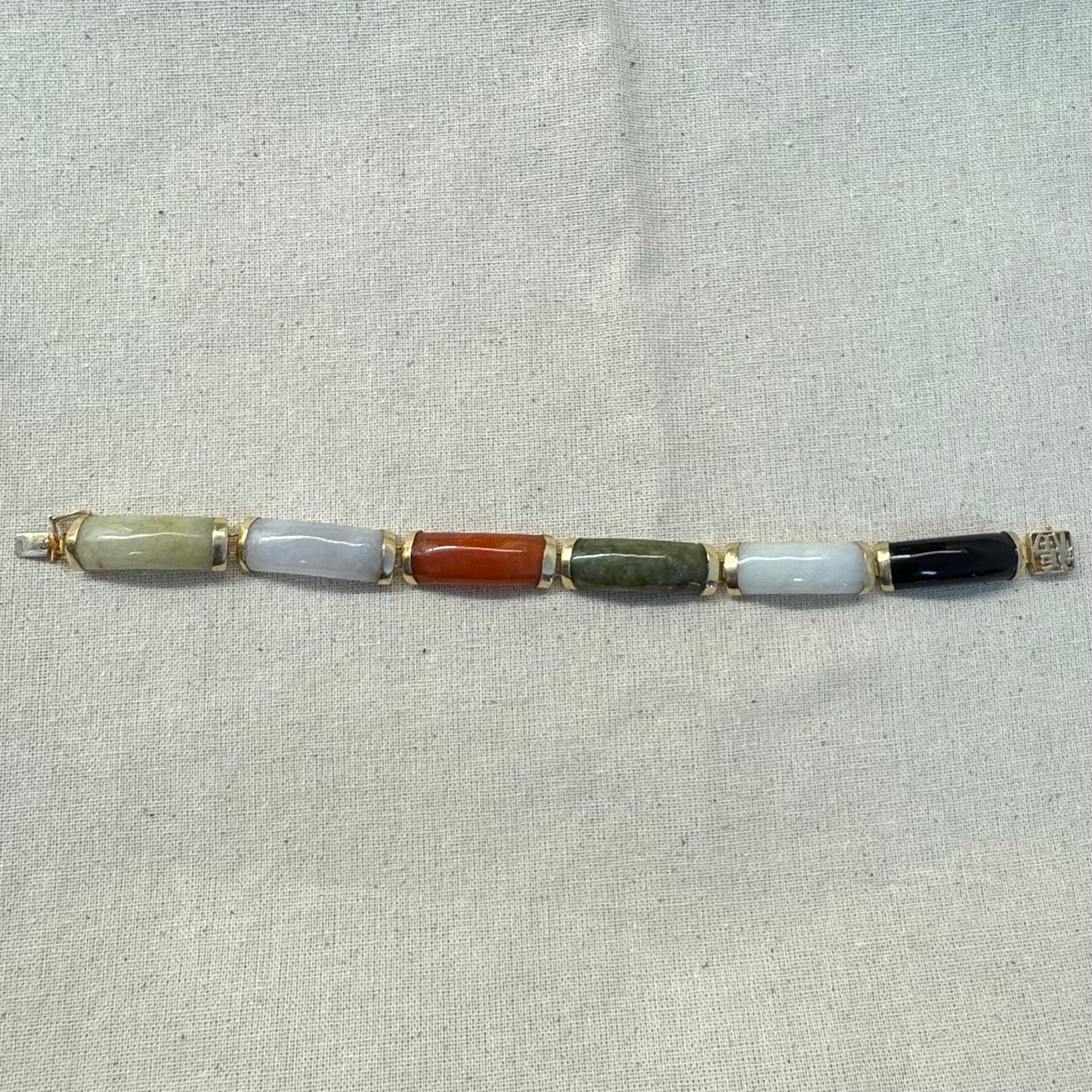 צמיד זהב צהוב 14 קראט עשוי מקטעי ג’ייד (jade) בשלושה גוונים – ירקרק, לבן ואדום – בשיבוץ זהב.