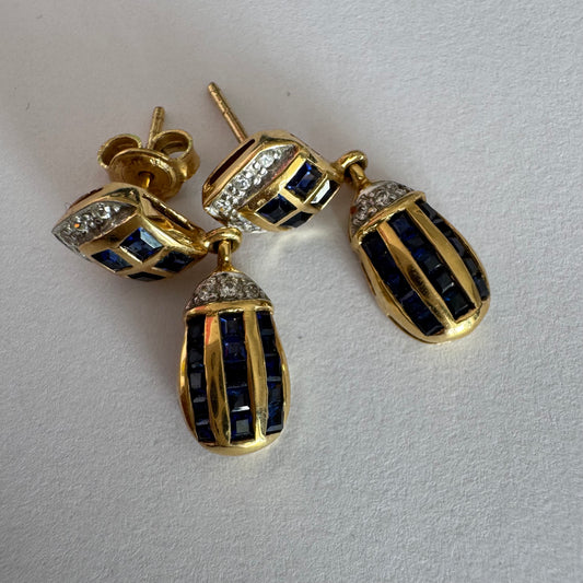 עגילי זהב צהוב 18 קראט תלויים, משובצים אבני ספיר כחולות בגוון כחול עמוק בעיצוב גיאומטרי, בשילוב יהלומים מנצנצים