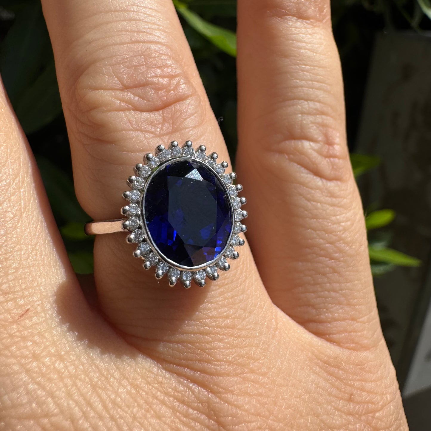 14K gold ring set with a deep blue oval Sapphire surrounded by a halo of sparkling Diamonds