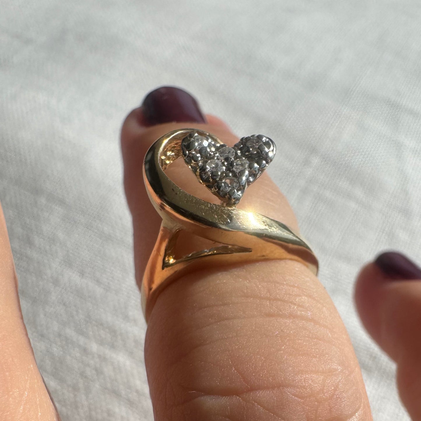14K gold ring featuring a Diamond-studded heart embraced by a flowing golden curve.
