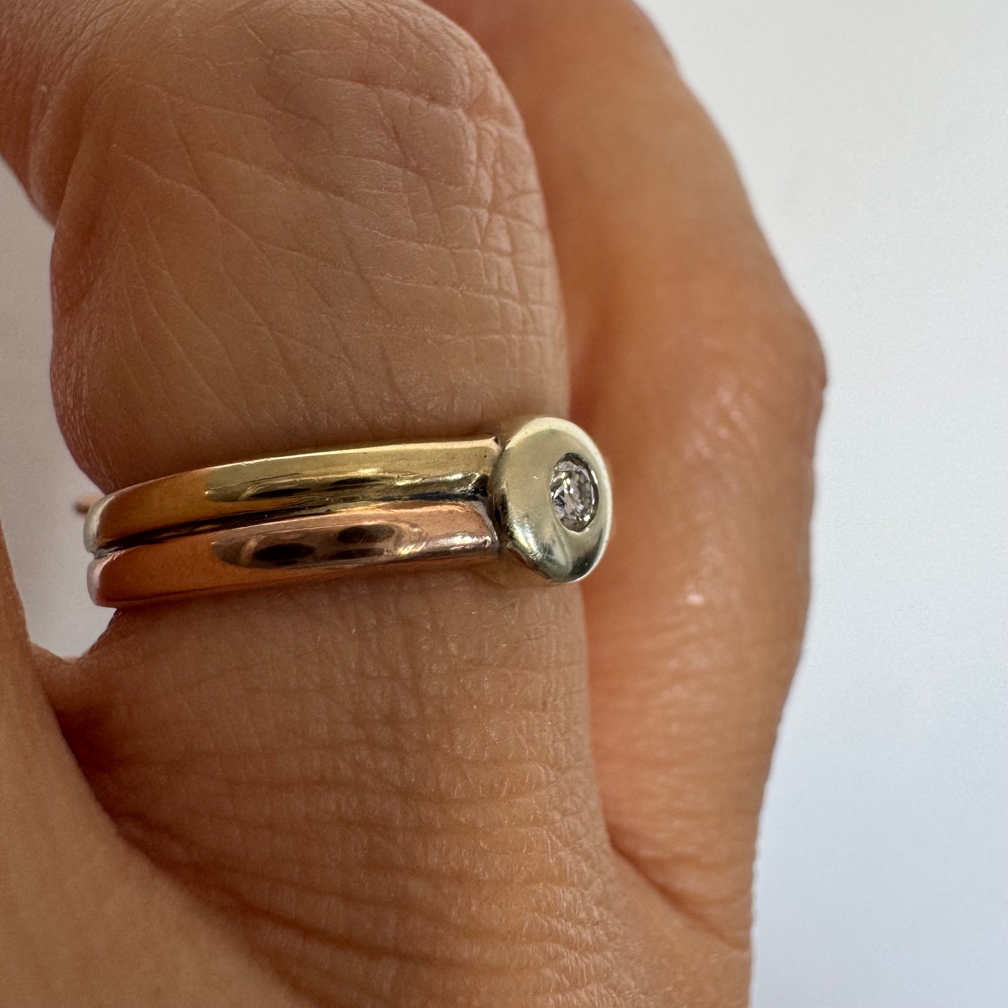 טבעת זהב 10 קראט בעיצוב מינימליסטי ונקי, משובצת יהלום מרכזי במסגרת חלקה (Bezel).