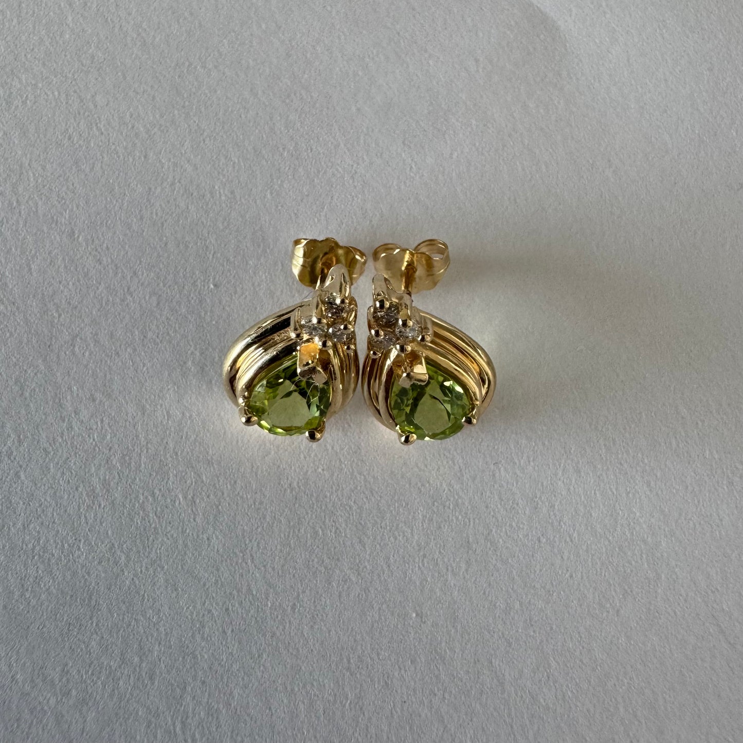 עגילי זהב צהוב 14 קראט משובצים אבני פרידוט בחיתוך טיפה, בגוון ירוק רענן ובוהק. 