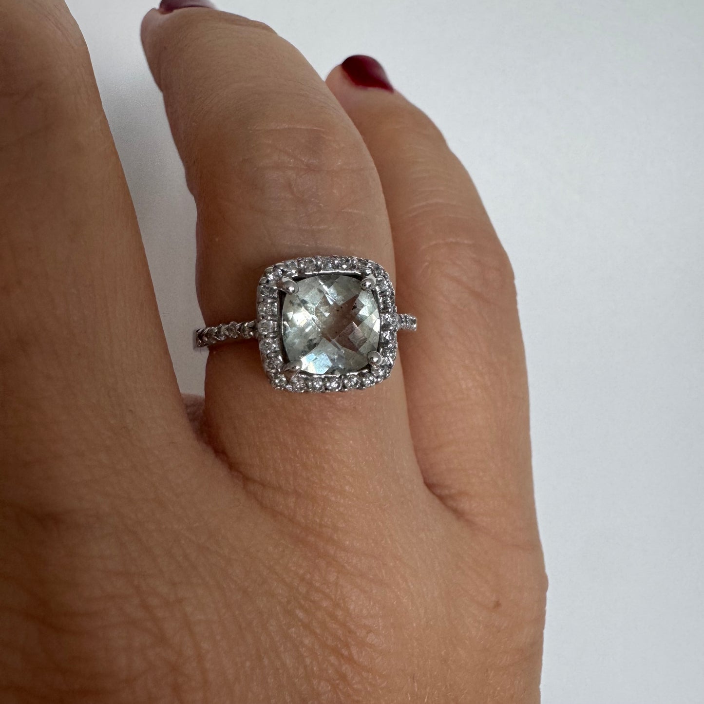 טבעת זהב לבן 14 קראט משובצת באבן אקוומרין בגוון תכלת ומוקפת במסגרת כפולה של יהלומים עגולים מנצנצים.