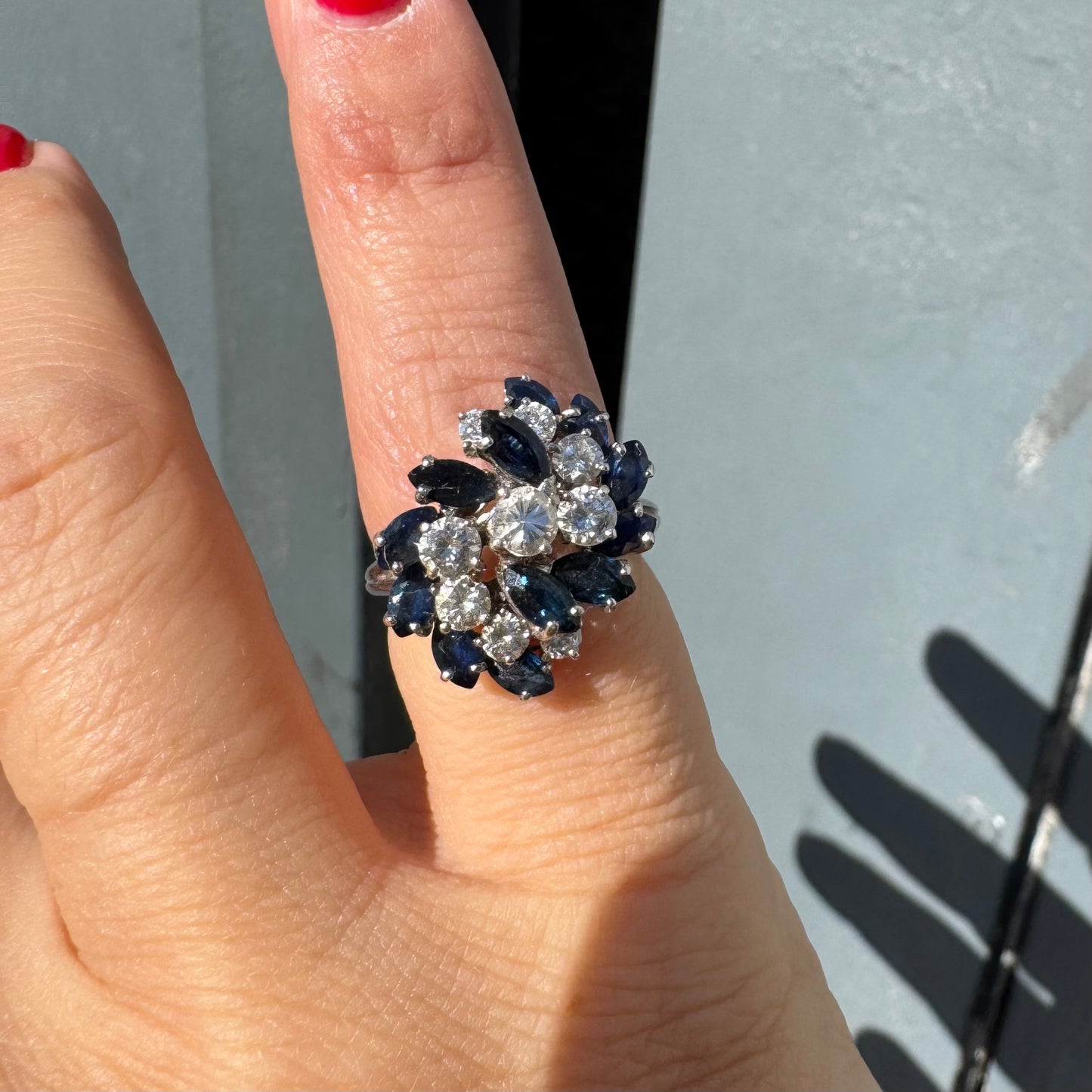 טבעת זהב לבן 18 קראט, משובצת אבני ספיר כחולות בחיתוך מרקיזה ויהלומים עגולים, בעיצוב אשכול קלאסי ואלגנטי.