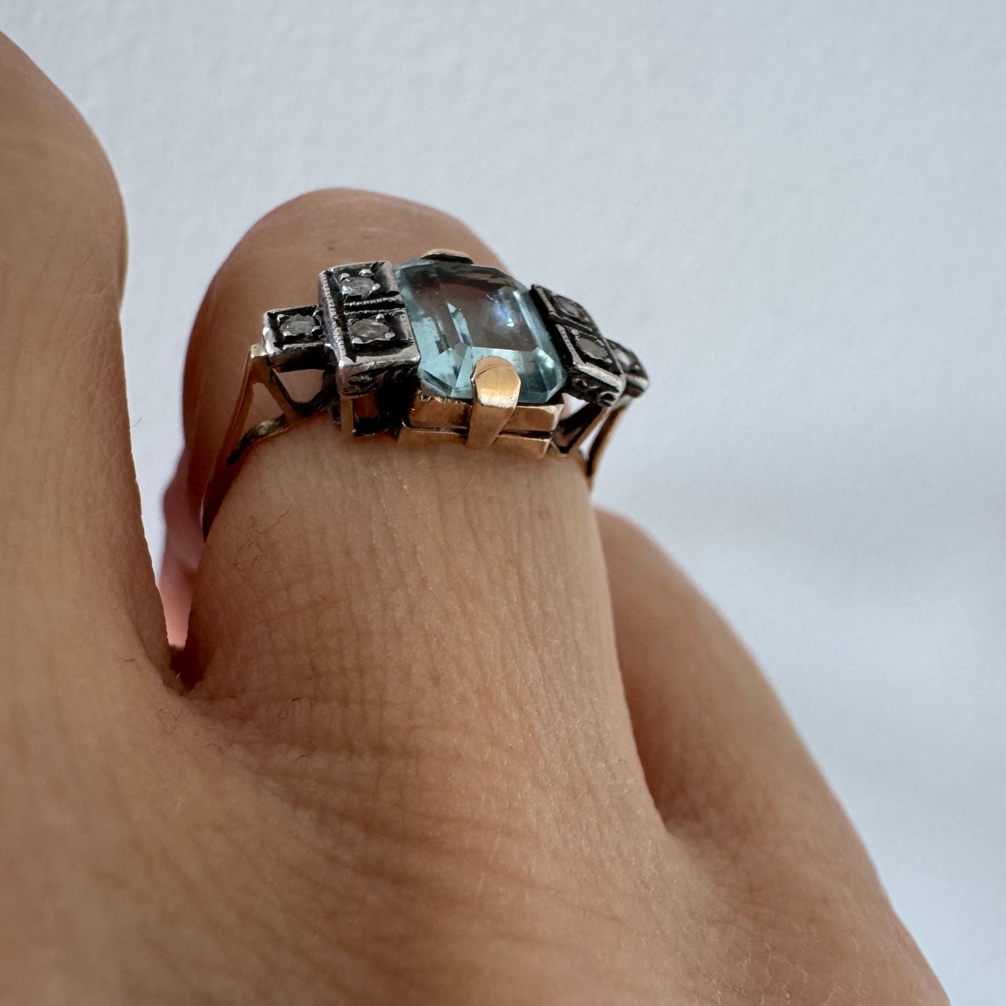 טבעת עתיקה מזהב 14 קראט, משובצת אבן אקוומרין מרכזית בחיתוך מלבני ויהלומים.