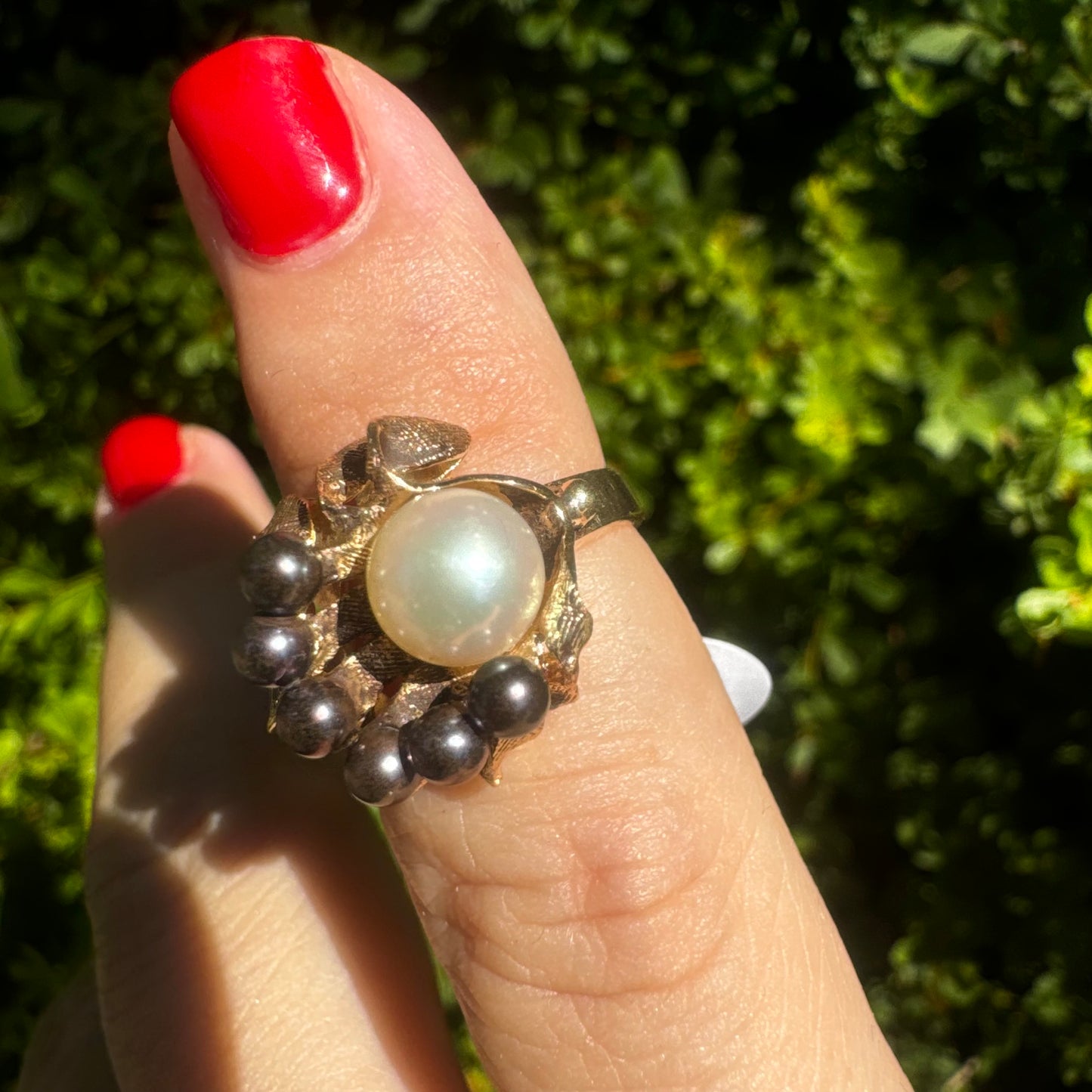14K gold ring set with a luminous white Pearl at its center surrounded by a delicate circle of black Pearls.