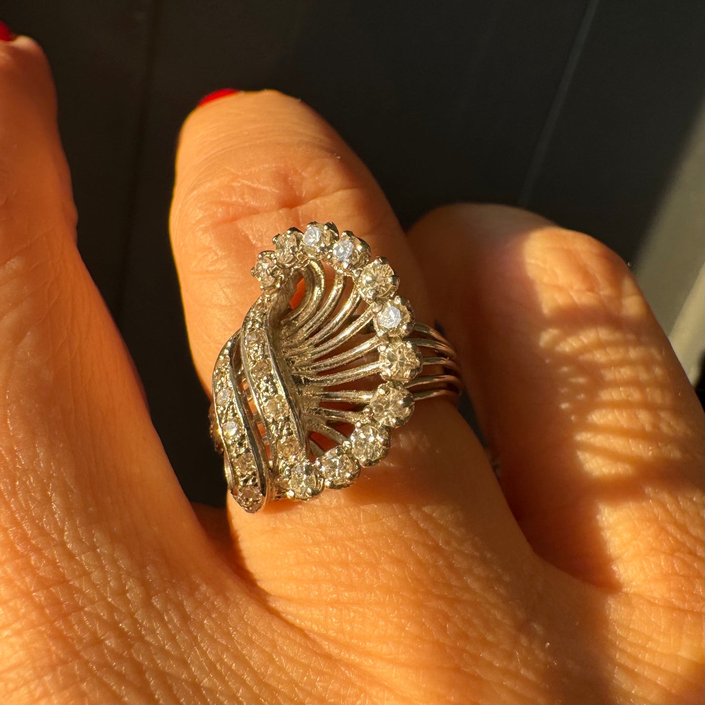 טבעת זהב 18 קראט משובצת יהלומים בעיצוב ייחודי ודינמי, עם קווים פתוחים ומניפת יהלומים היקפית היוצרת מראה עשיר ומלא ברק