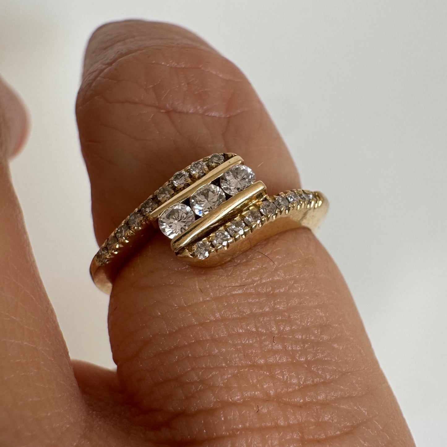 טבעת זהב צהוב 14 קראט בעיצוב ייחודי, משובצת שלושה יהלומים מרכזיים ושורות נוספות של יהלומים לאורך הזרועות. 