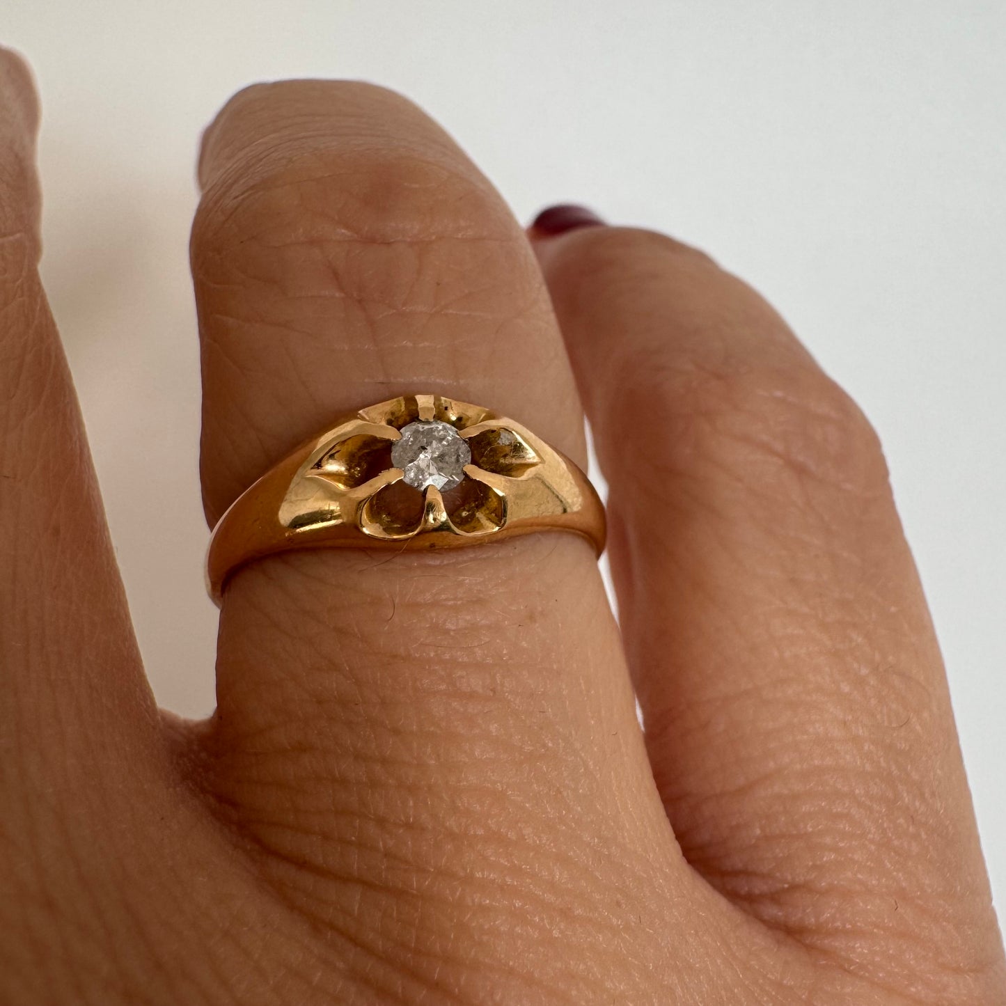 טבעת זהב צהוב 18 קראט בעיצוב פרח עדין, משובצת יהלום מרכזי בתוך עלי כותרת פתוחים.