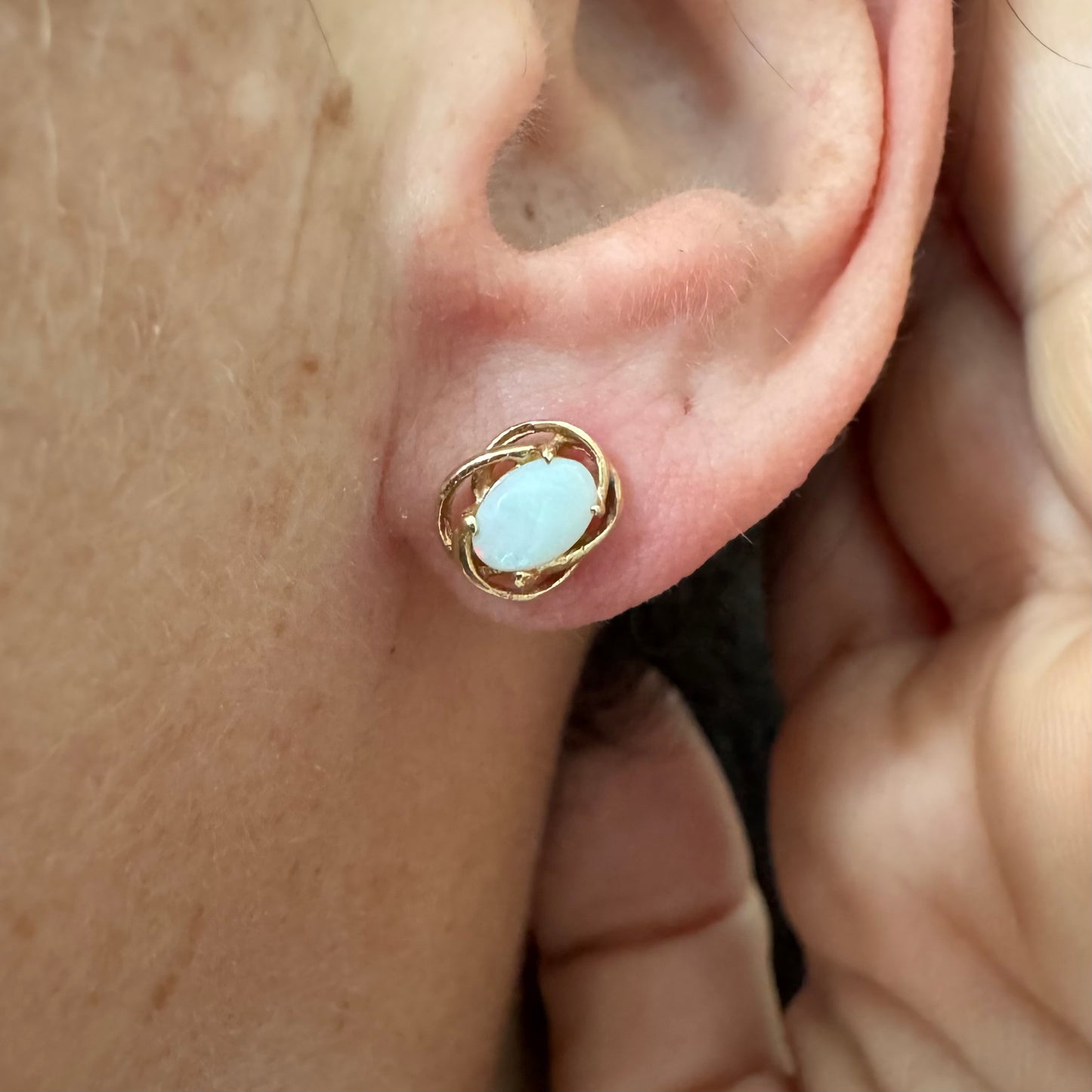 עגילי זהב צהוב 14 קראט משובצים אבני אופל אובליות בגוון לבן חלבי עם משחקי צבע טבעיים ועדינים.