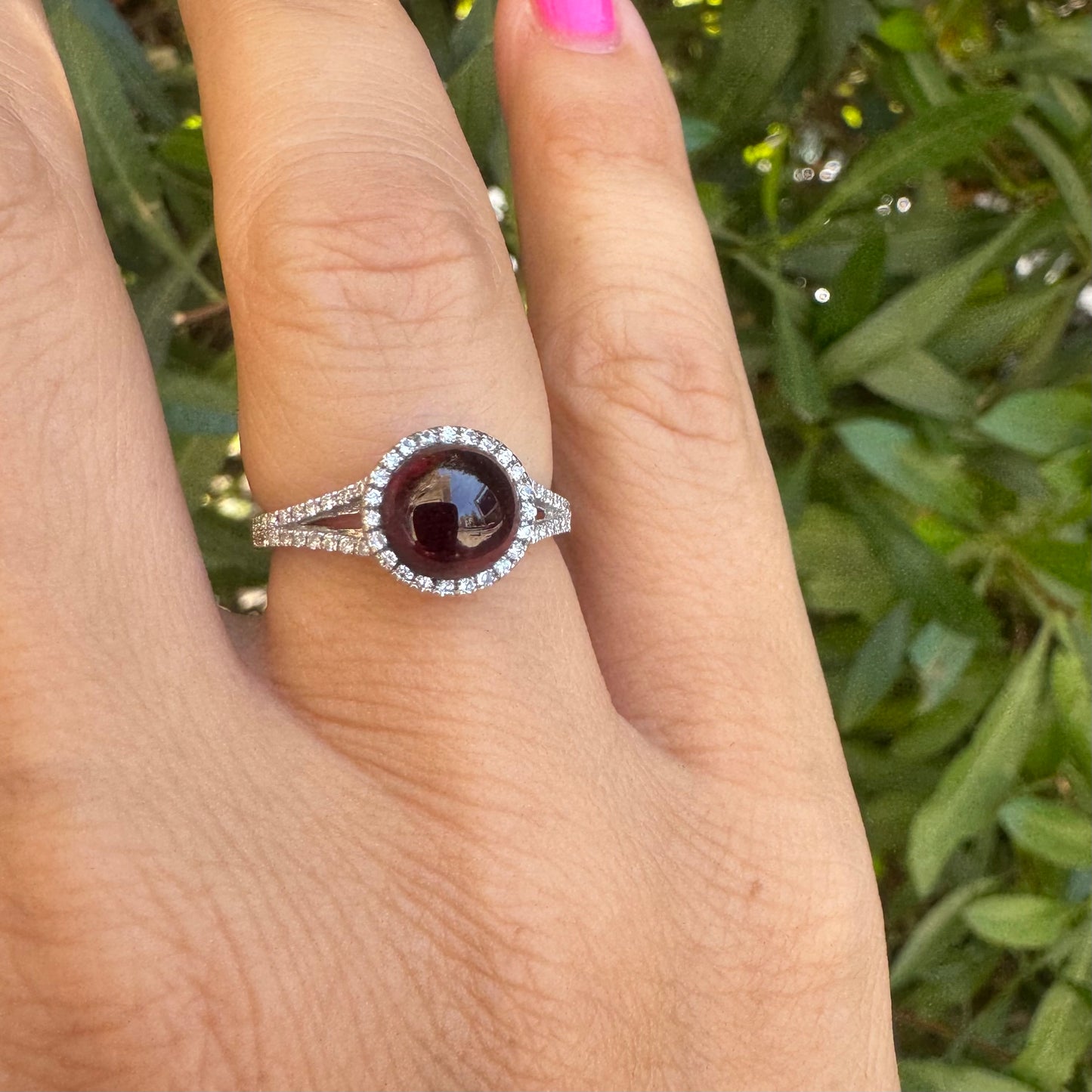 14K gold ring set with a deep red cabochon Garnet, surrounded by a halo of sparkling Diamonds