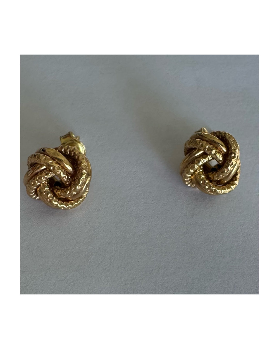 עגילי זהב צהוב 18 קראט בעיצוב קשר פיסולי, עם טקסטורה עשירה המדגישה את עומק וצורת הזהב.