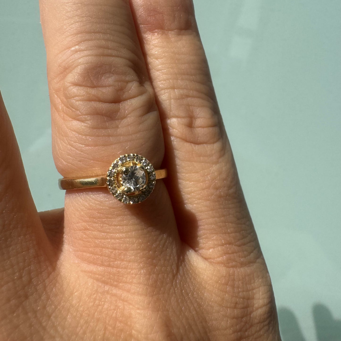 14K gold ring featuring a round central Diamond, surrounded by a sparkling halo of smaller Diamonds.