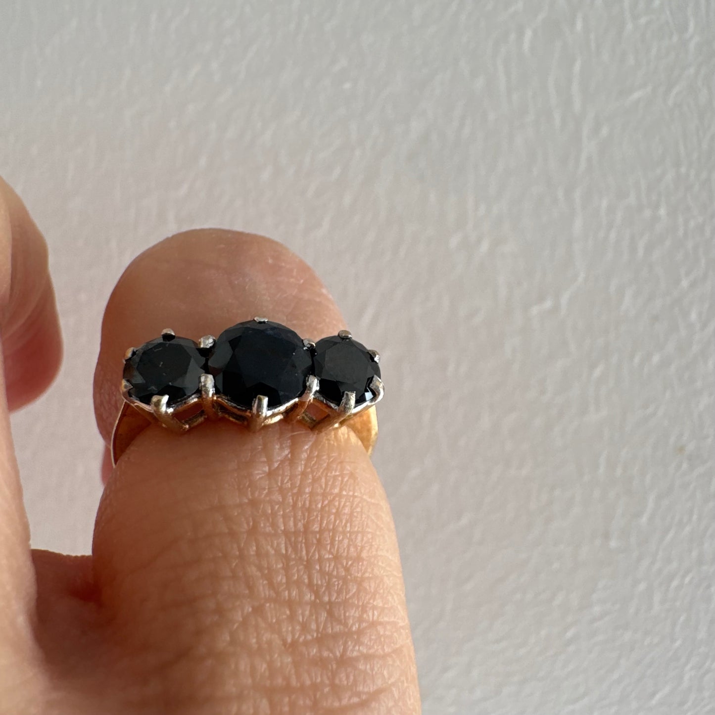 טבעת זהב 10 קראט משובצת שלוש אבני ספיר בצבע כחול כהה בחיתוך עגול, בעיצוב קלאסי עם נוכחות עמוקה ואלגנטית.