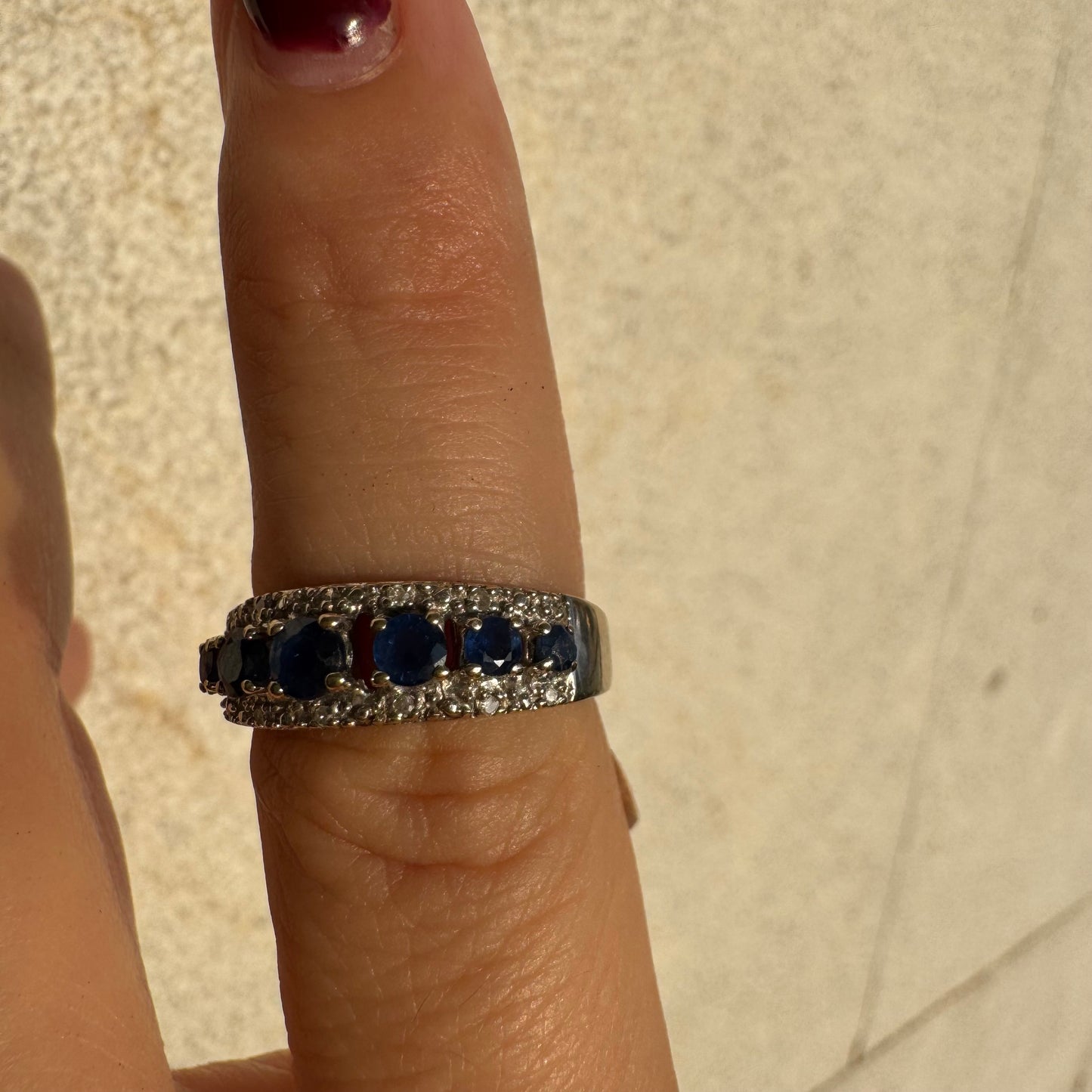 18K gold ring set with deep blue sapphires in a classic round cut, framed by two shimmering rows of brilliant Diamonds.