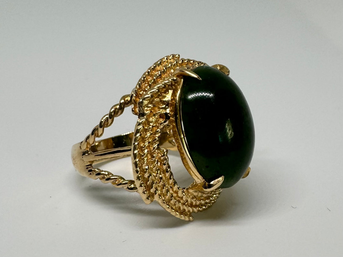 14K gold ring set with a deep green Jade set in a textured gold frame.