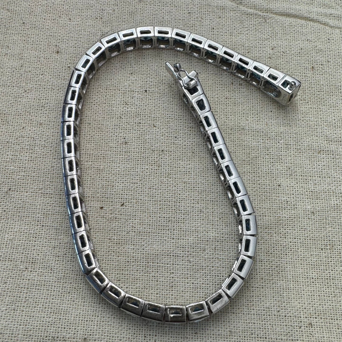 צמיד זהב לבן 18 קראט של המותג ה.שטרן משובץ אבני טופז כחולה&nbsp;בשיבוץ ערוץ חלק וקלאסי – פריט נצחי עם טאץ’ מודרני