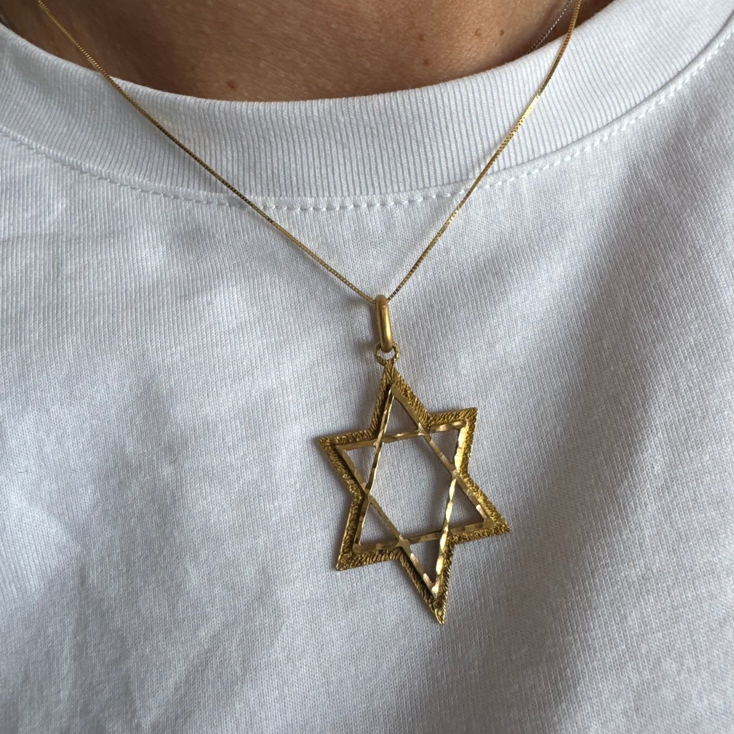 תליון מגן דוד מזהב צהוב 14 קראט בעיצוב פתוח, עם טקסטורה עדינה בשוליים המוסיפה עומק ואופי.