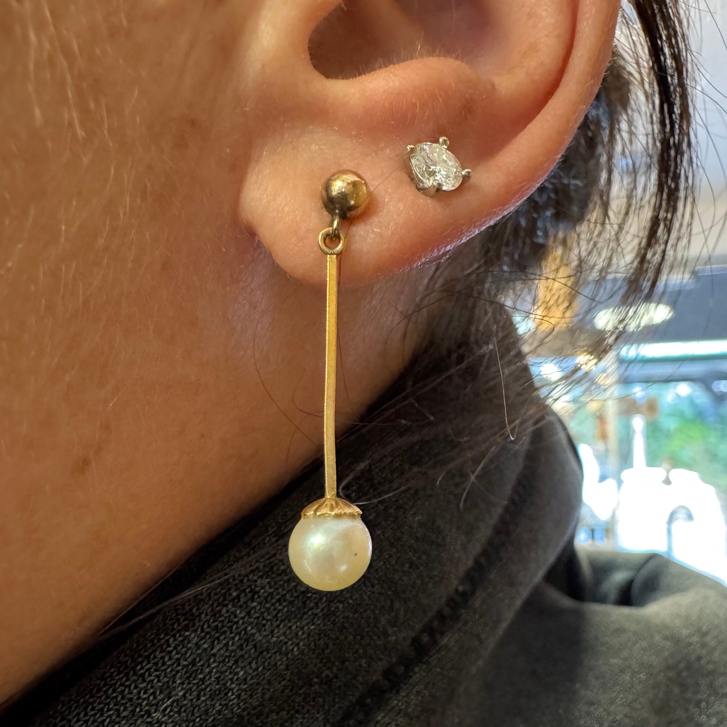 עגילי זהב 14 קראט בעיצוב תלוי ועדין, עם פנינה עגולה בקצה.