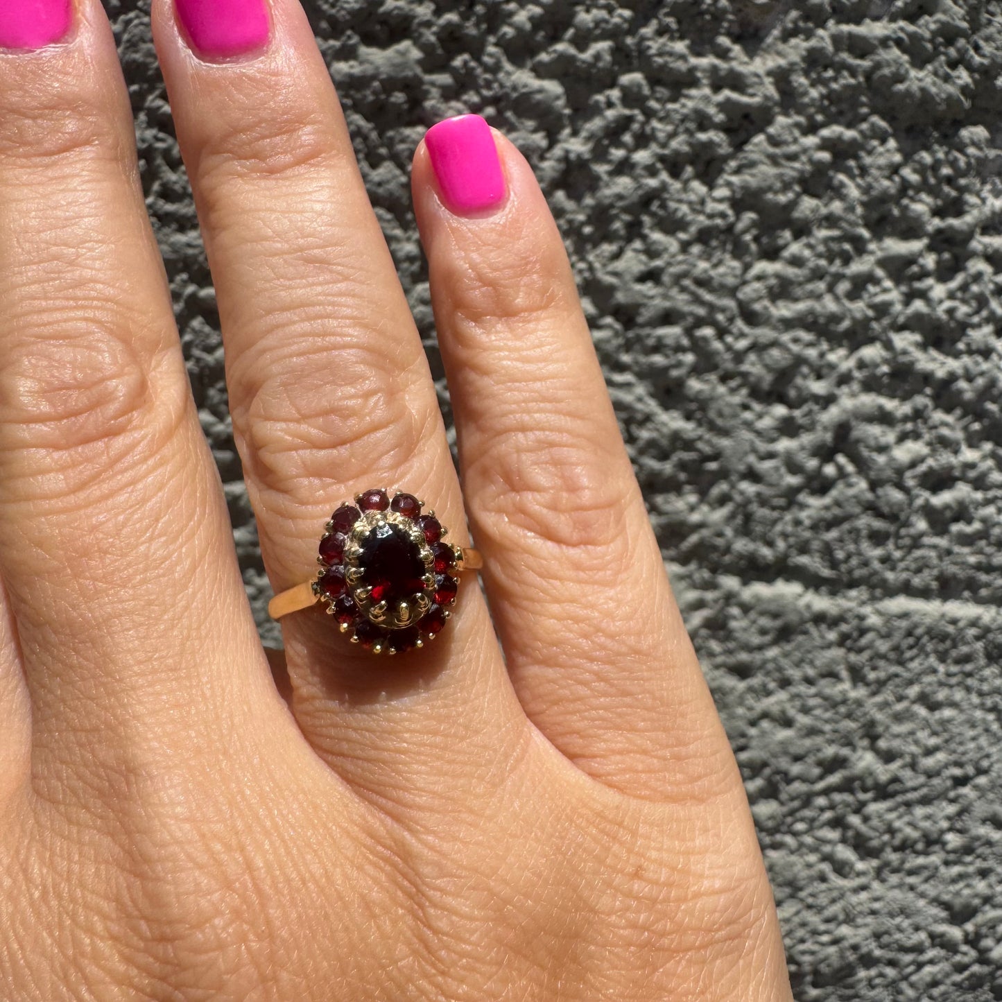 18K gold ring set with an oval garnet center stone, surrounded by smaller garnets