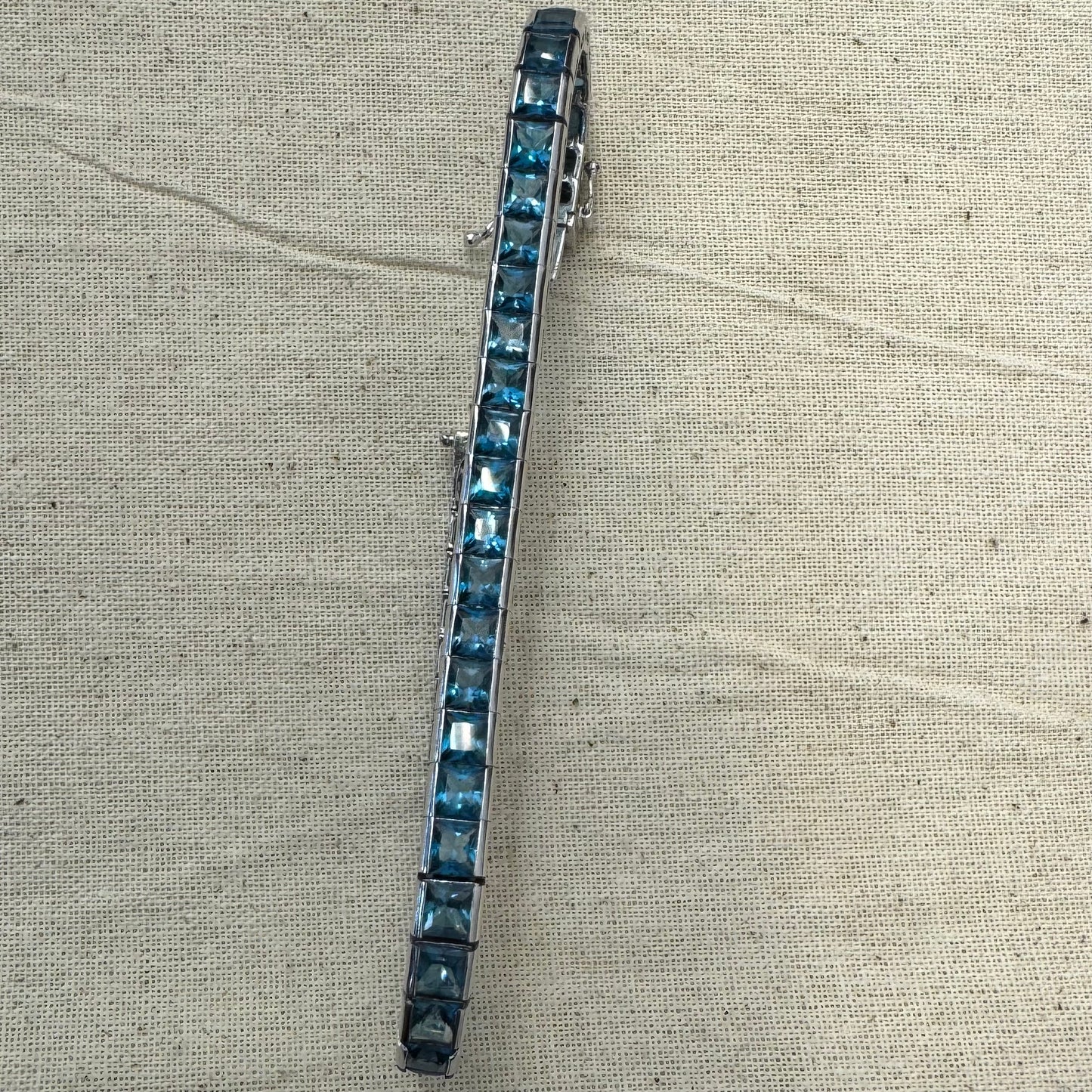 צמיד זהב לבן 18 קראט של המותג ה.שטרן משובץ אבני טופז כחולה&nbsp;בשיבוץ ערוץ חלק וקלאסי – פריט נצחי עם טאץ’ מודרני