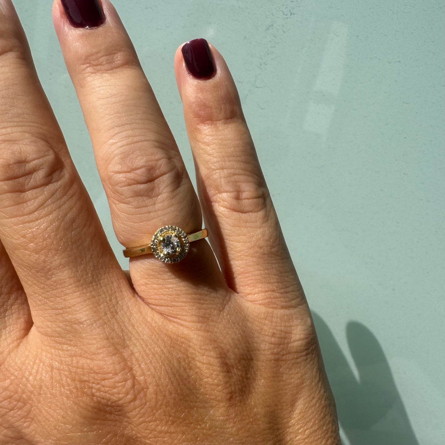 14K gold ring featuring a round central Diamond, surrounded by a sparkling halo of smaller Diamonds.