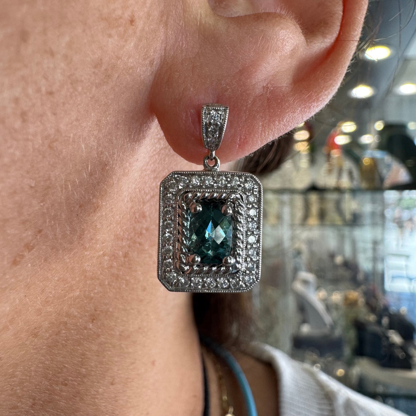 14K gold drop earrings set with emerald-cut Blue Topaz, surrounded by a halo of sparkling Diamonds