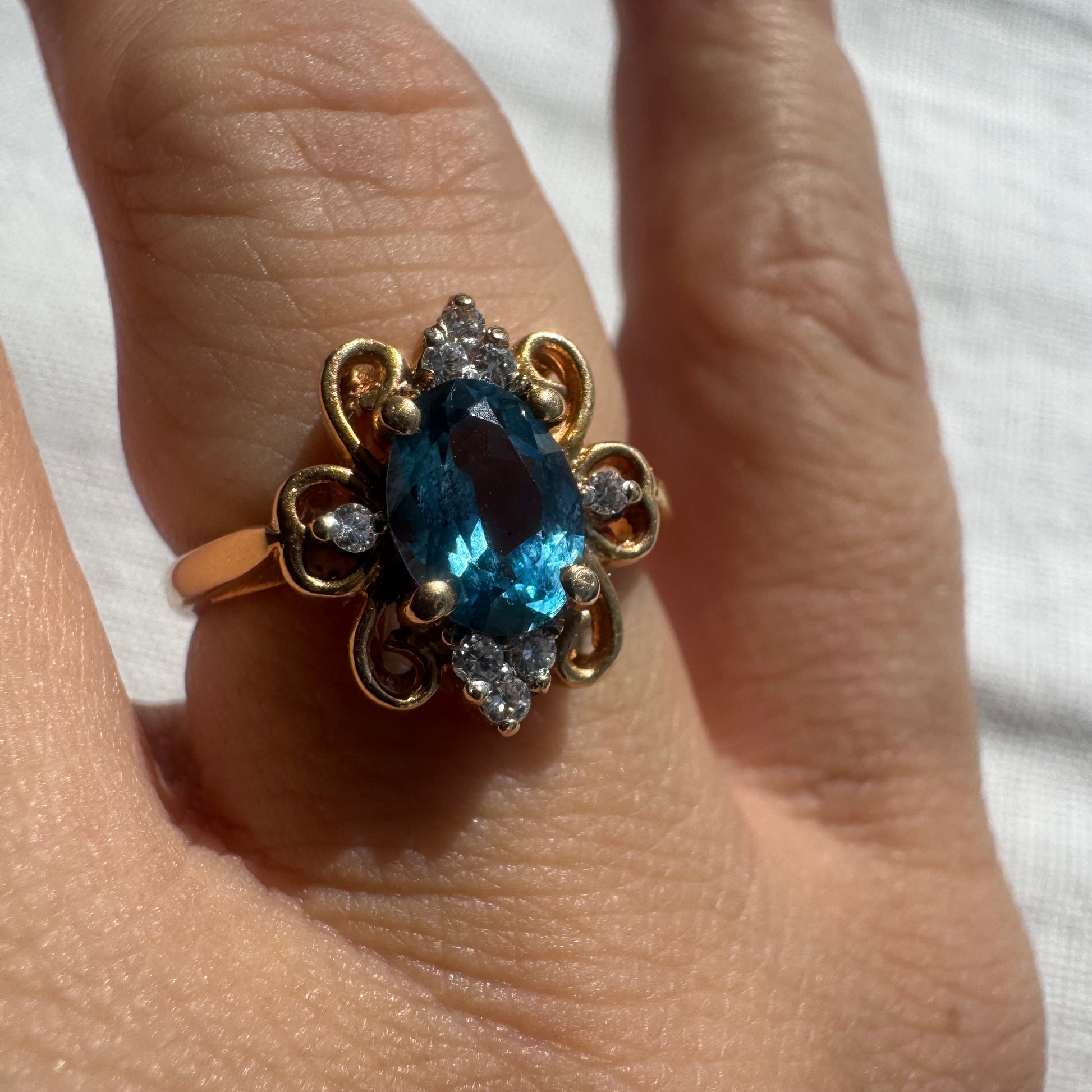 טבעת זהב צהוב 18 קראט בעלת נוכחות מרשימה, משובצת אבן טופז כחולה בחיתוך אובלי ויהלומים