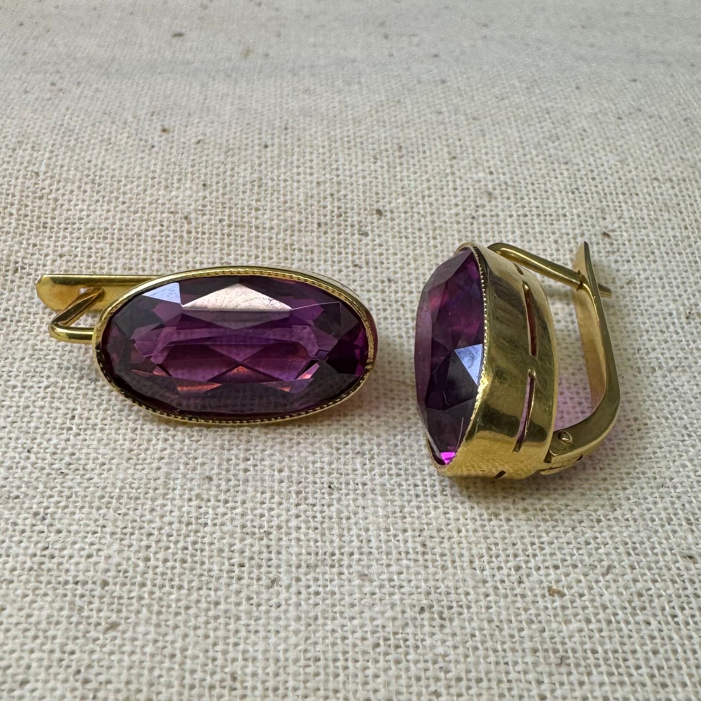 עגילי זהב צהוב 18 קראט, תלויים קצרים, משובצים באבני אמטיסט סגולות בחיתוך אובלי עמוק.