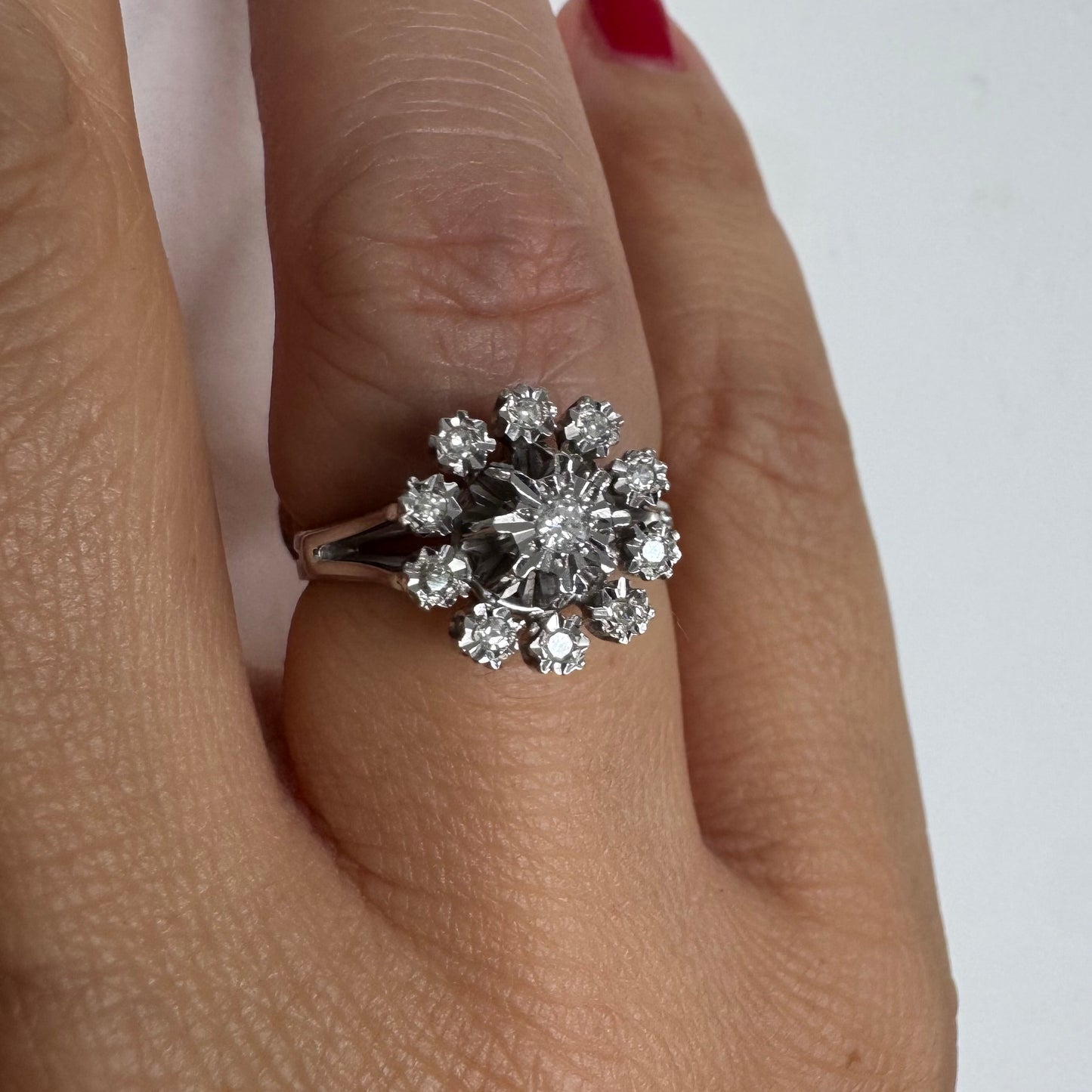 טבעת זהב 18 קראט משובצת יהלום מרכזי מוקף יהלומים נוספים בעיצוב פרח סימטרי ומרשים