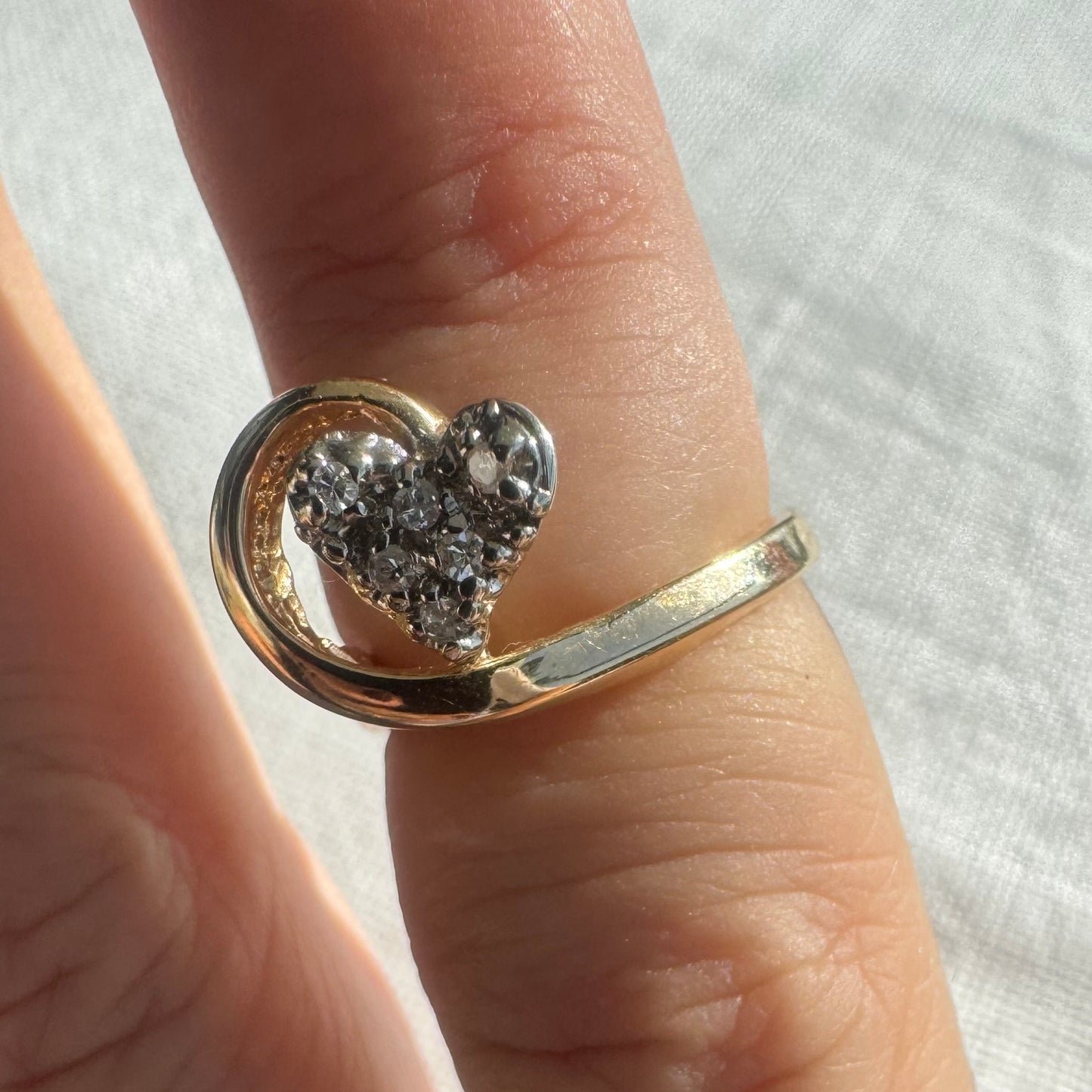 14K gold ring featuring a Diamond-studded heart embraced by a flowing golden curve.