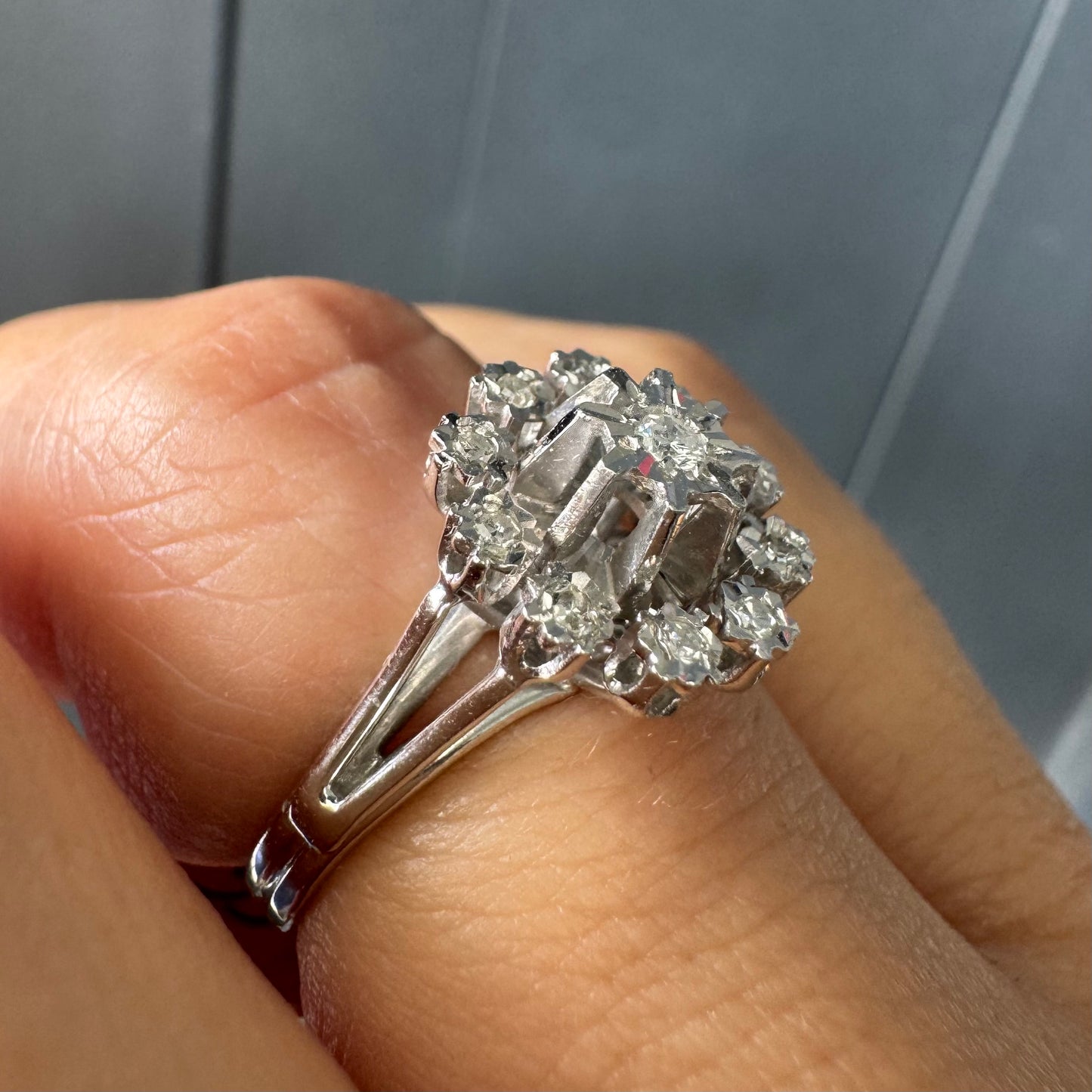 טבעת זהב 18 קראט משובצת יהלום מרכזי מוקף יהלומים נוספים בעיצוב פרח סימטרי ומרשים