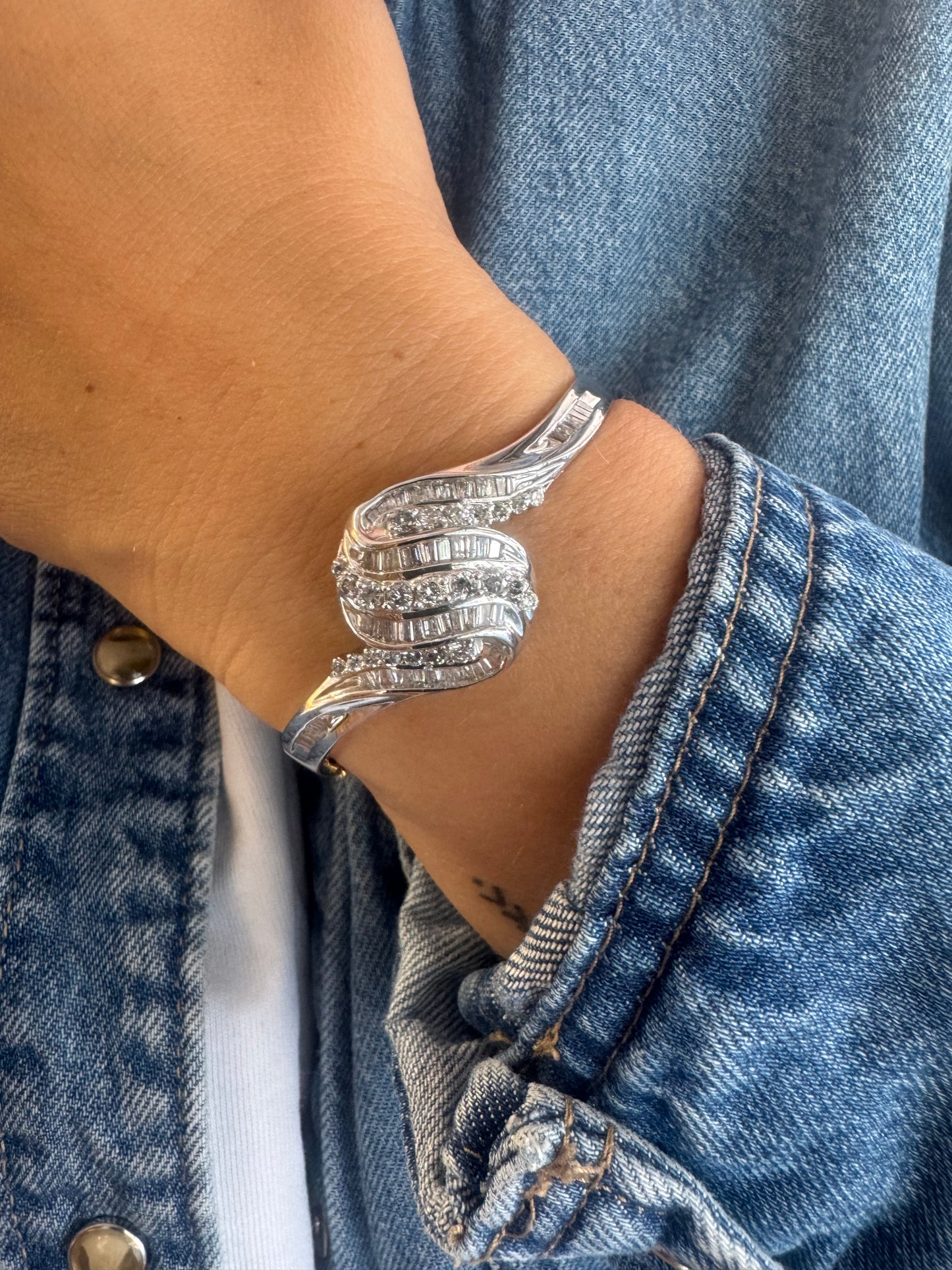 צמיד מרהיב מזהב לבן 14 קראט, בעיצוב גלים דינמי המשובץ בשיבוץ מרוכב של יהלומים עגולים ובחיתוך באגט.