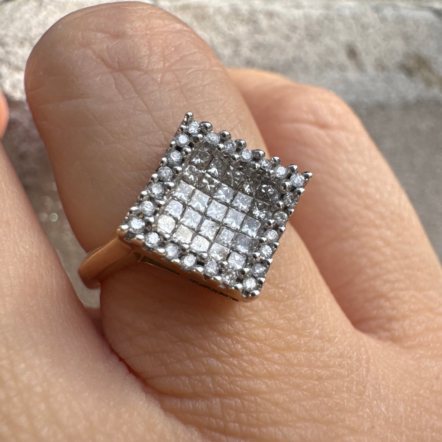 טבעת זהב 14 קראט בעיצוב ריבועי משובצת יהלומים בחיתוך פרינסס ומוקפת מסגרת יהלומים עגולים. 