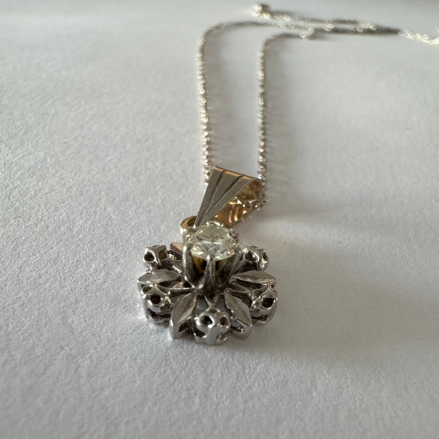 תליון זהב 14 קראט משובץ יהלום מרכזי בעיצוב פרח עדין ומלא נוכחות.