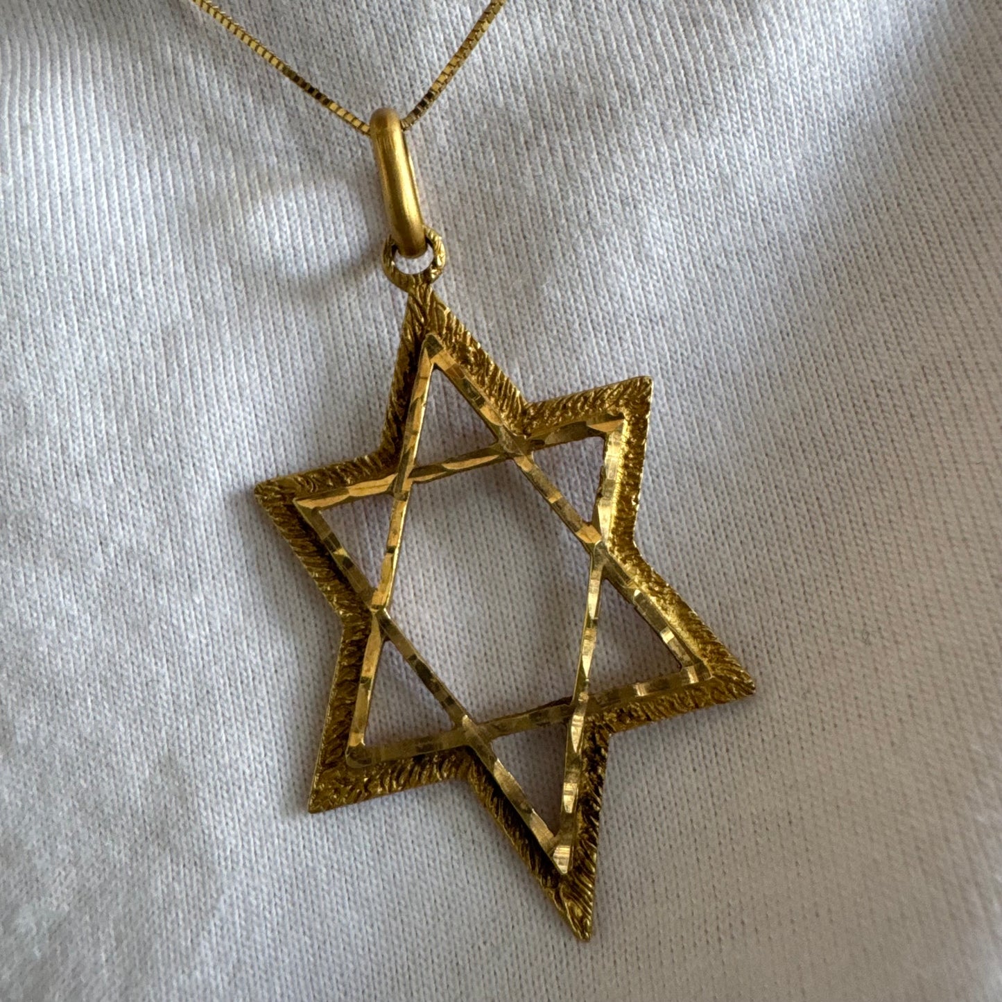 תליון מגן דוד מזהב צהוב 14 קראט בעיצוב פתוח, עם טקסטורה עדינה בשוליים המוסיפה עומק ואופי.