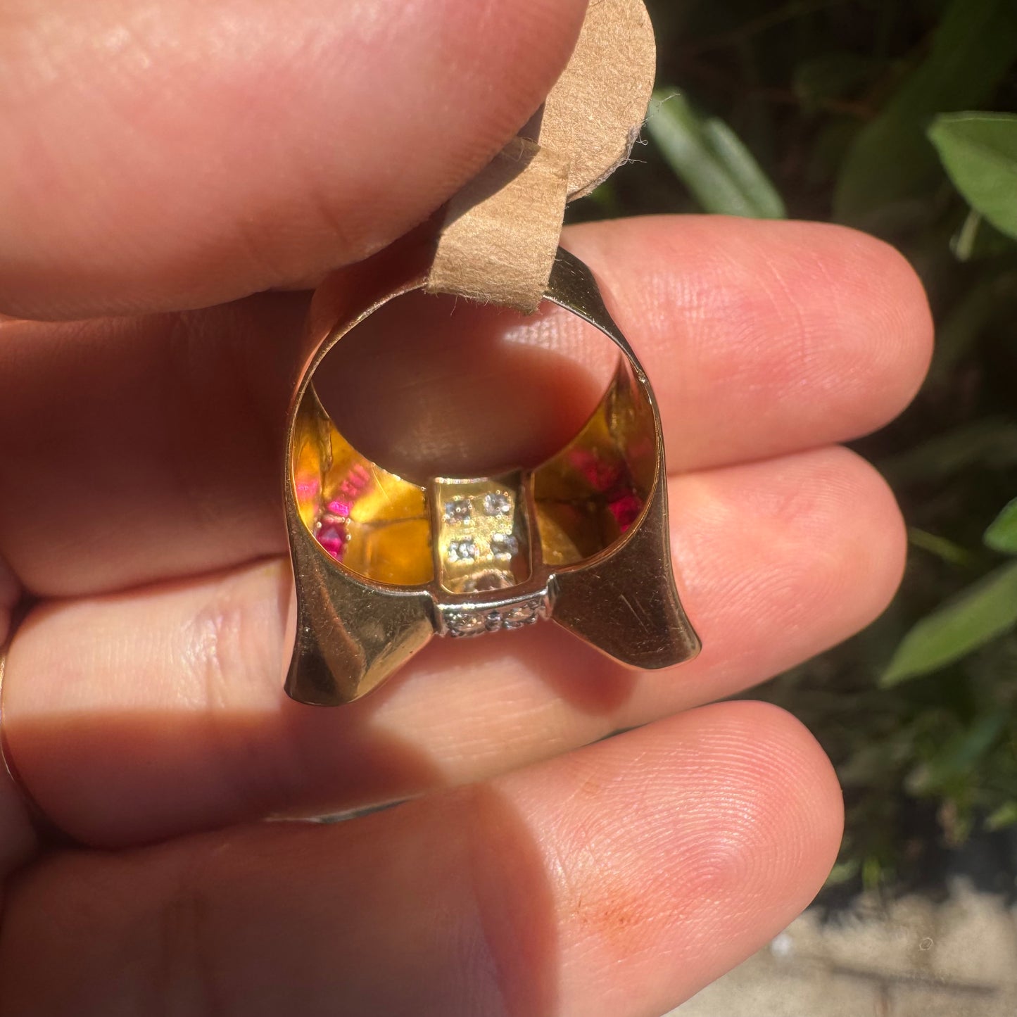 18K gold bow-shaped ring set with pavé Diamonds at the center and rows of square-cut Rubies on the sides.