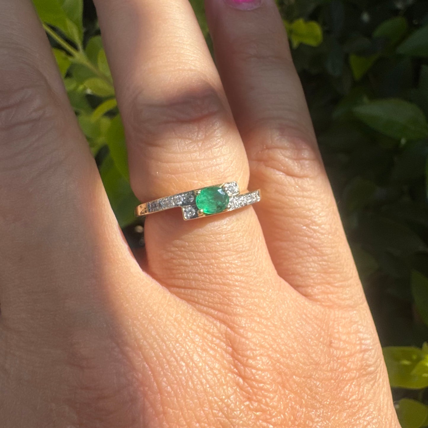 18K gold ring set with an oval green Emerald at the center, accented with sparkling Diamonds along the band.