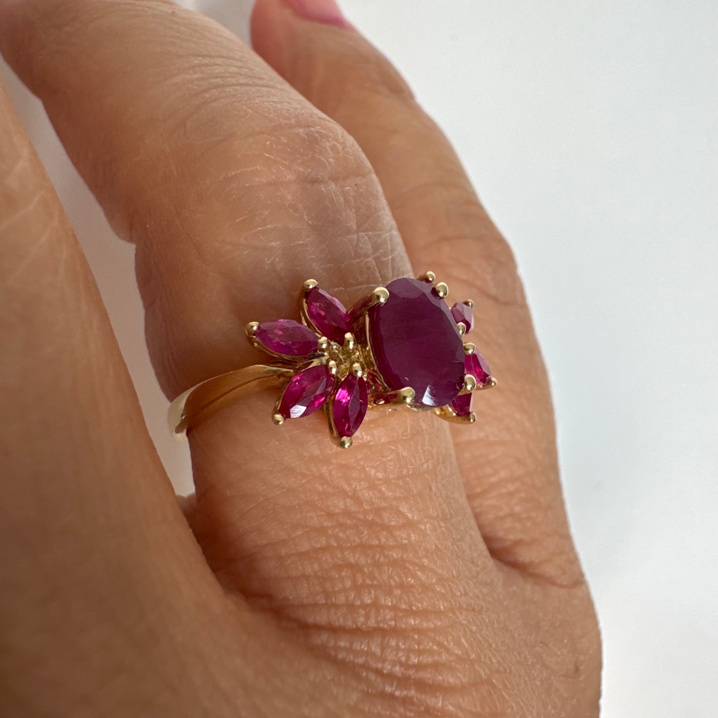 טבעת זהב צהוב 14 קראט משובצת רובי מרכזי גדול ולצידו רובי בחיתוך מרקיזה בעיצוב פרחוני עשיר.