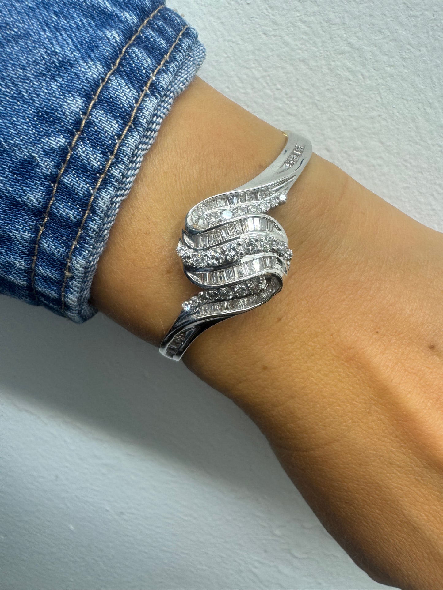 צמיד מרהיב מזהב לבן 14 קראט, בעיצוב גלים דינמי המשובץ בשיבוץ מרוכב של יהלומים עגולים ובחיתוך באגט.