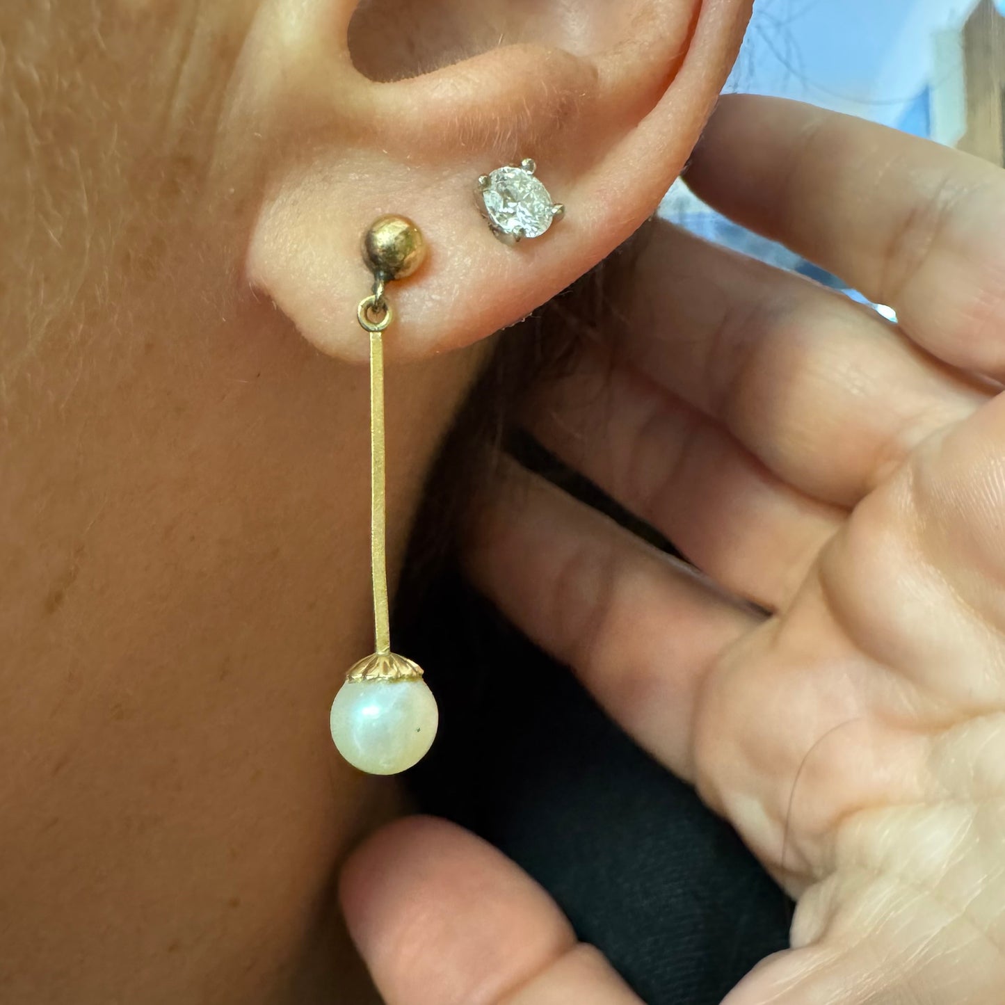 עגילי זהב 14 קראט בעיצוב תלוי ועדין, עם פנינה עגולה בקצה.