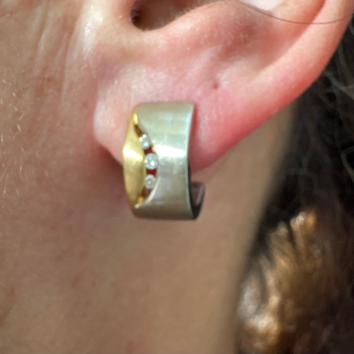 עגילי זהב 18 קראט משובצים יהלומים בעיצוב מודרני ונקי עם שילוב של שני גוונים וגימור מאט יוקרתי.