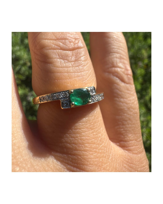 טבעת זהב צהוב 18 קראט משובצת אמרלד ירוק אובלי במרכז ומשובצת יהלומים נוצצים לאורך החישוק