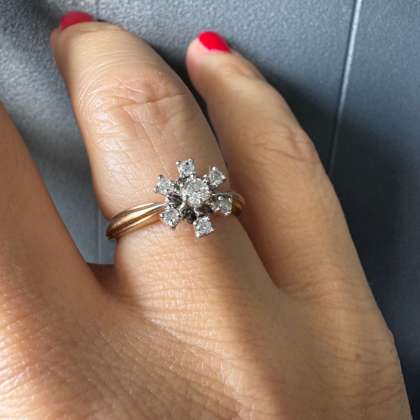 טבעת זהב 9 קראט משובצת יהלום מרכזי ויהלומים מסביב בעיצוב פרח קלאסי.