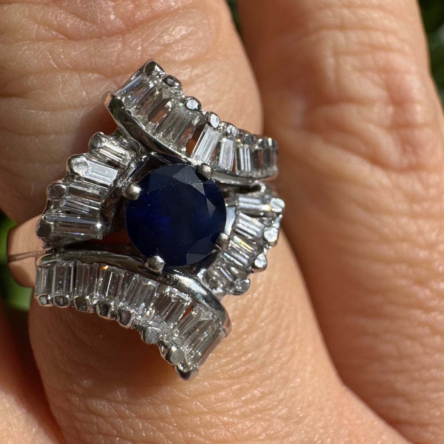 14K gold ring set with a round deep blue sapphire at the center, surrounded by baguette cut Diamonds