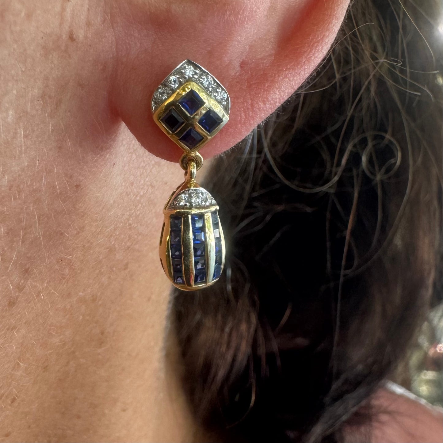 עגילי זהב צהוב 18 קראט תלויים, משובצים אבני ספיר כחולות בגוון כחול עמוק בעיצוב גיאומטרי, בשילוב יהלומים מנצנצים