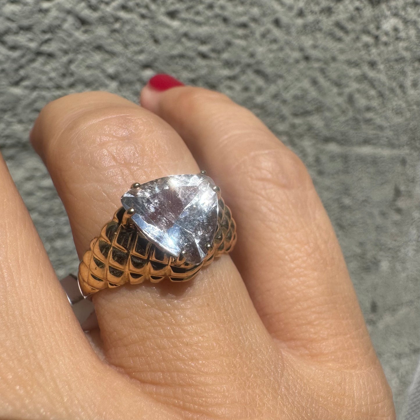 10K gold ring featuring a large, triangular-cut transparent gemstone set in a bold textured band