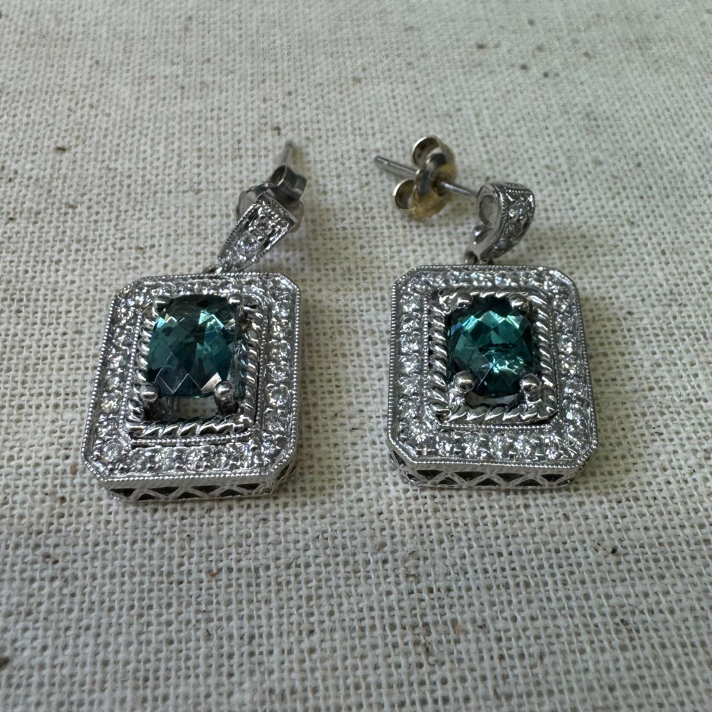 14K gold drop earrings set with emerald-cut Blue Topaz, surrounded by a halo of sparkling Diamonds